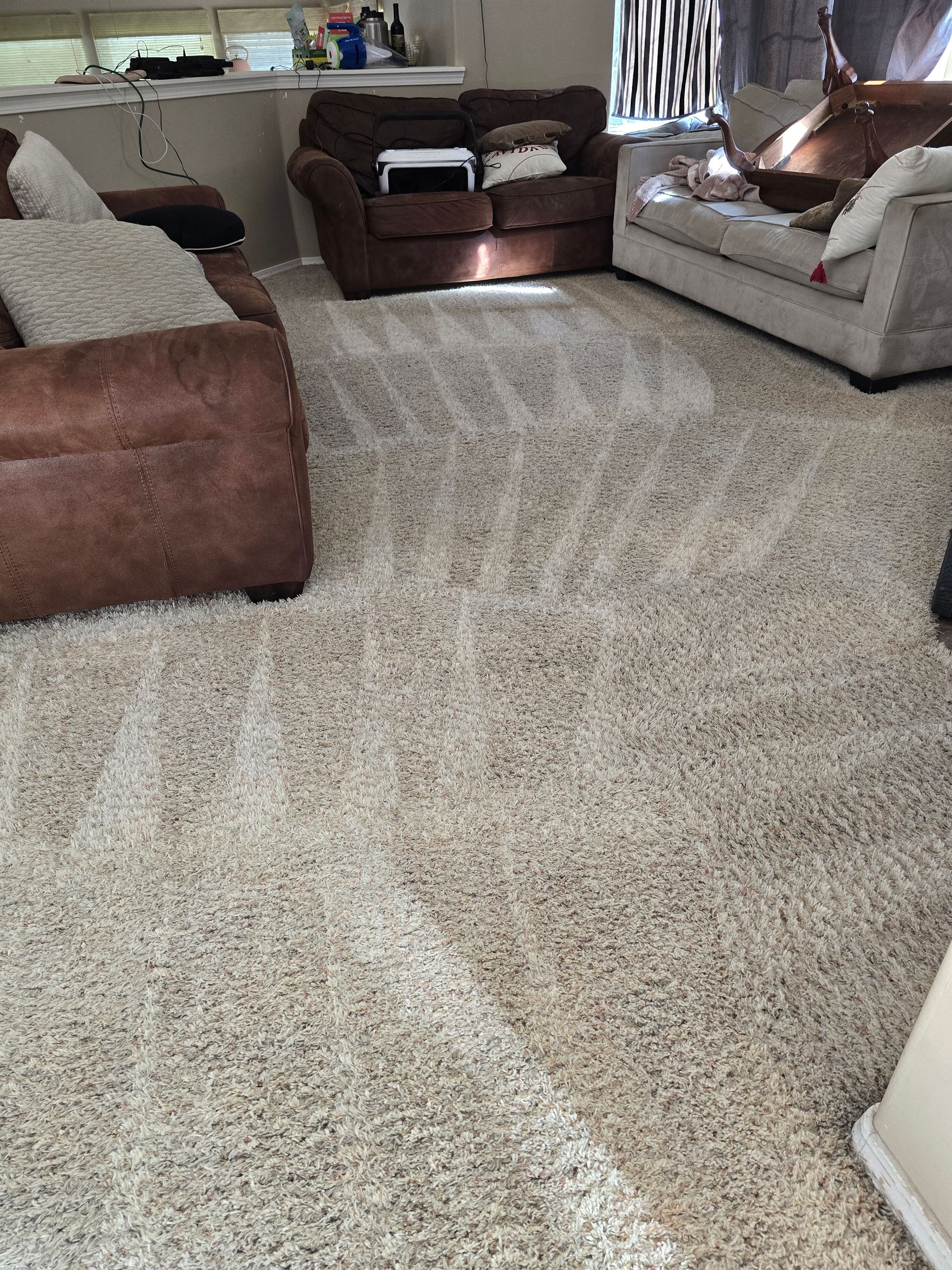 Living room with beige carpet, brown sofas, and a TV stand in the background