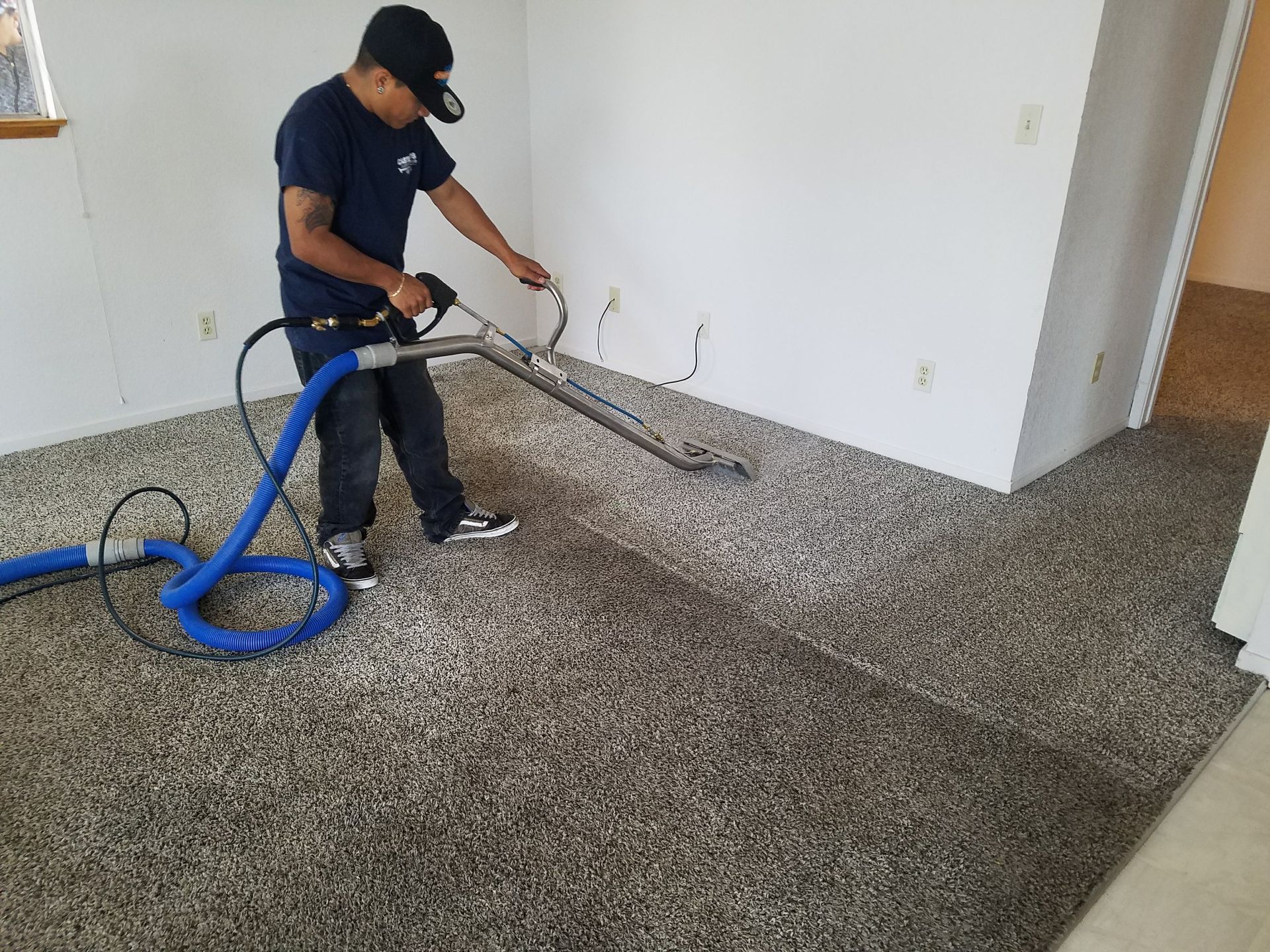 Worker vacuuming carpet during installation in an empty room
