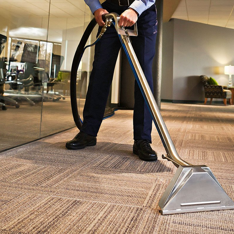 Office worker cleaning carpet with a floor extractor in a lobby